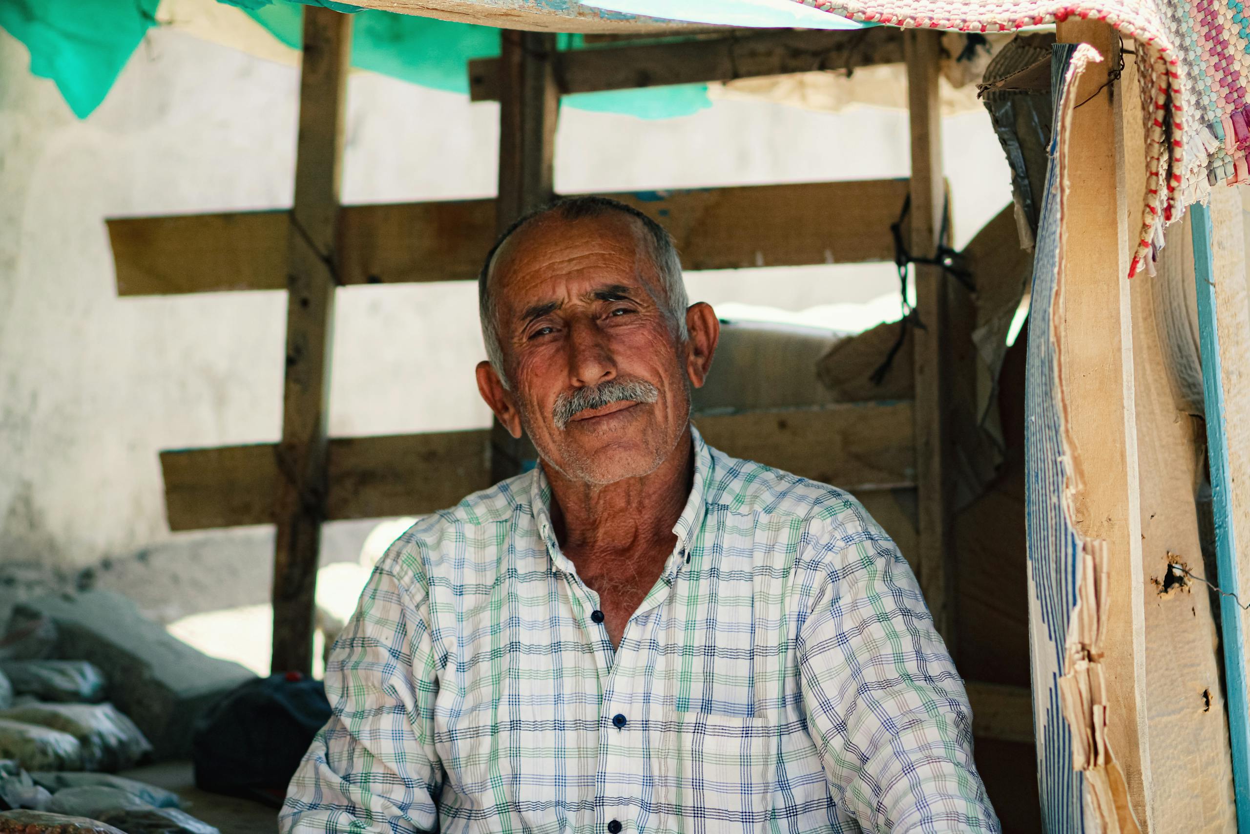 Senior man with mustache sitting in a rustic setting, exuding warmth and wisdom.