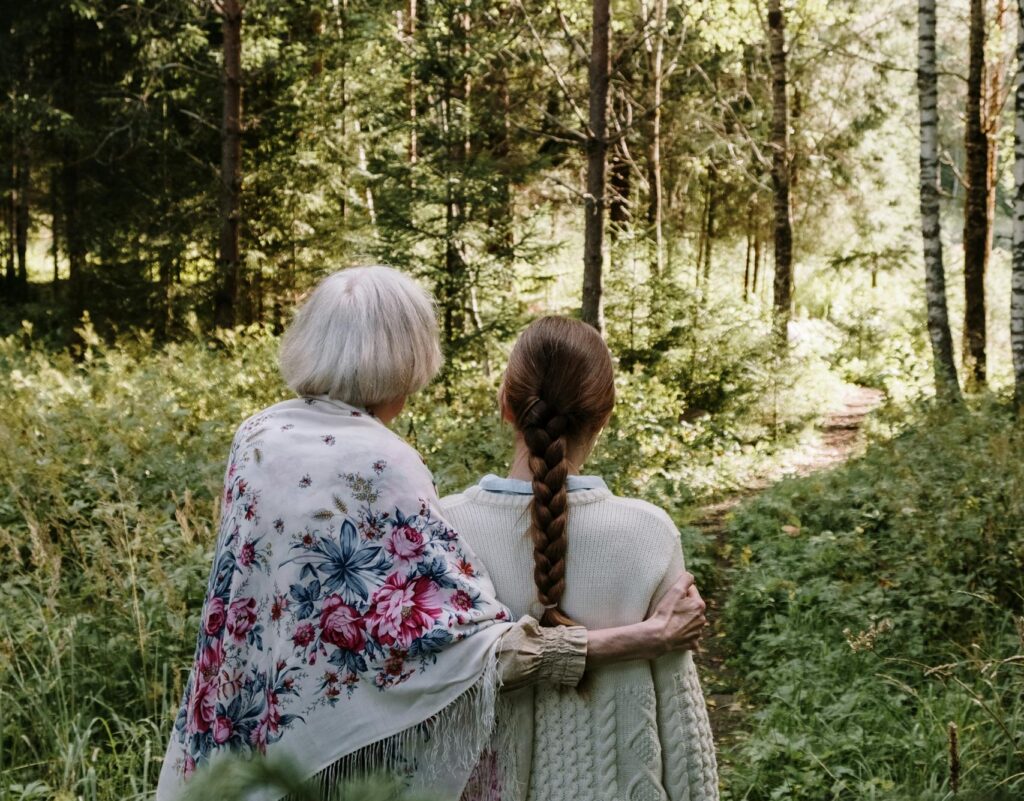 A serene moment of a grandmother and granddaughter strolling through a lush forest together.