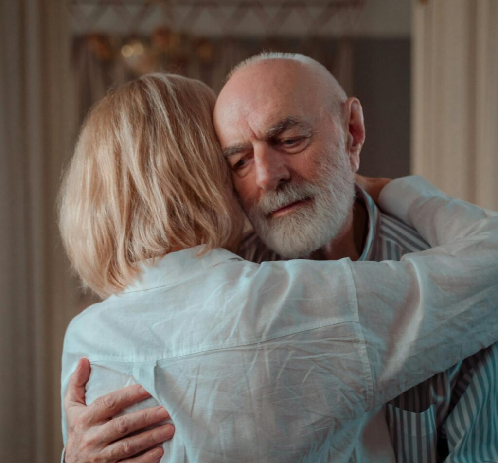 An elderly couple shares a warm embrace, symbolizing love and companionship.