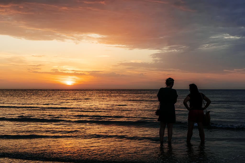 Adults enjoying a tranquil sunset on Middelkerke Beach, Belgium, with a vibrant sky.