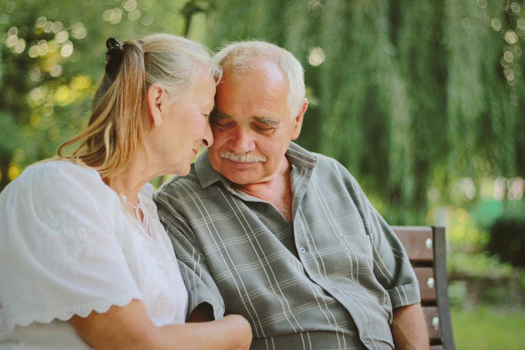 Elderly couple sitting closely, enjoying a joyful moment together in a serene outdoor setting.