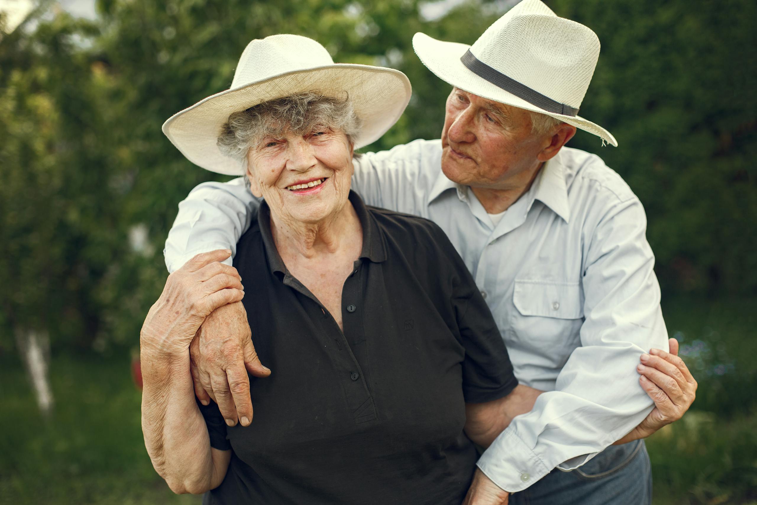 Happy senior couple in hats enjoying time together outdoors during a sunny day.