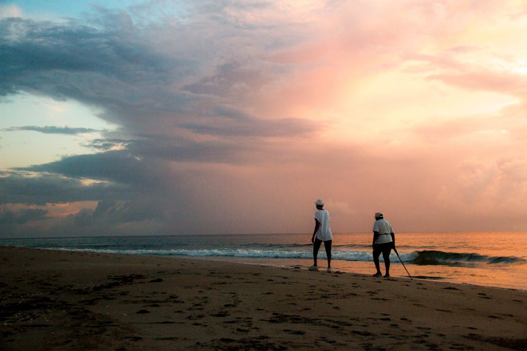 Two people walking along West Palm Beach at sunset, capturing a serene coastal atmosphere.