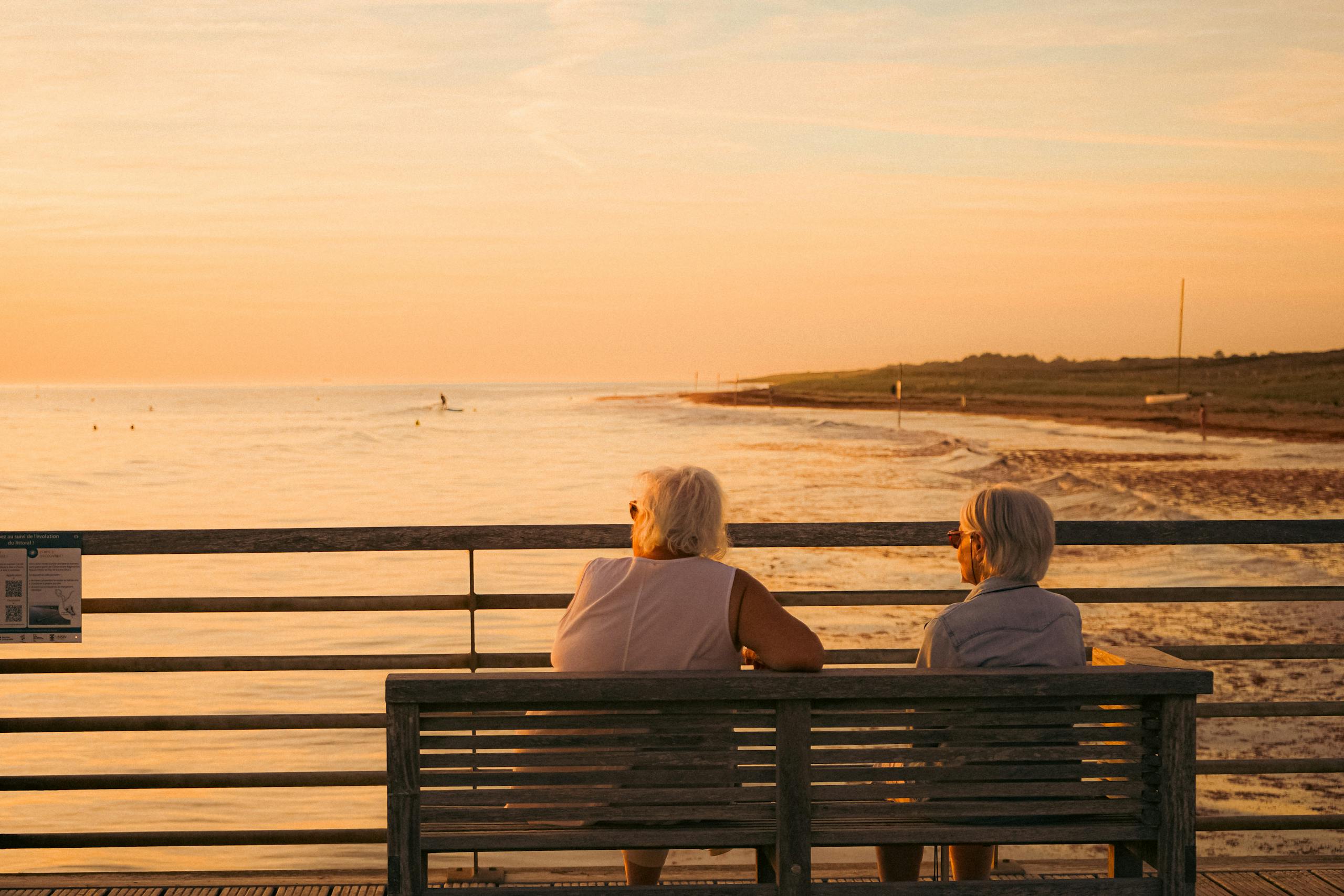 Elderly women enjoying a peaceful sunset on a French pier by the sea.
