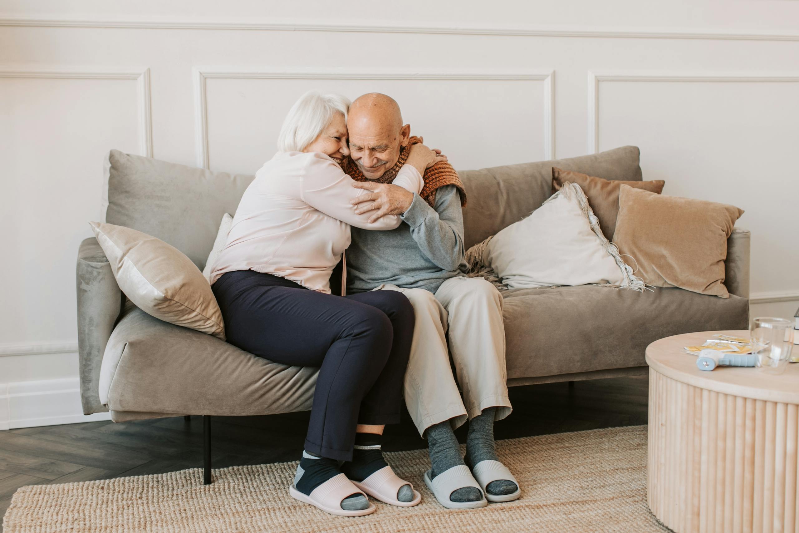 Tender moment of affection between a senior couple embracing on a comfortable couch indoors.