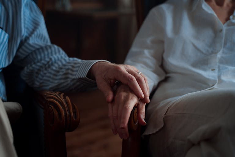 An intimate moment of an elderly couple holding hands, capturing love and companionship.